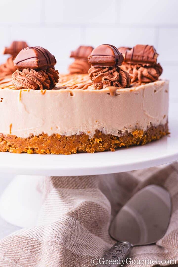 Kinder Bueno Cheesecake on a white cake stand.