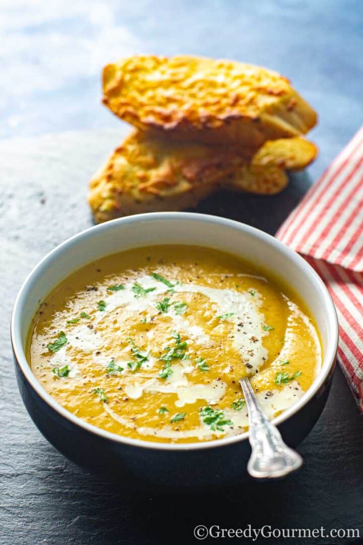 Creamy Navy bean soup served in a bowl with cheesy garlic bread.