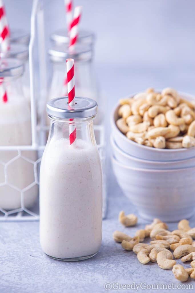 Cashew milk next to a bowl of cashews